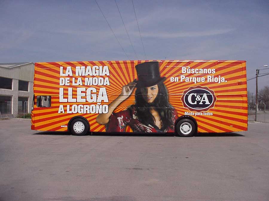 Autobús naranja estacionado con un C&A roadshow bus publicidad.