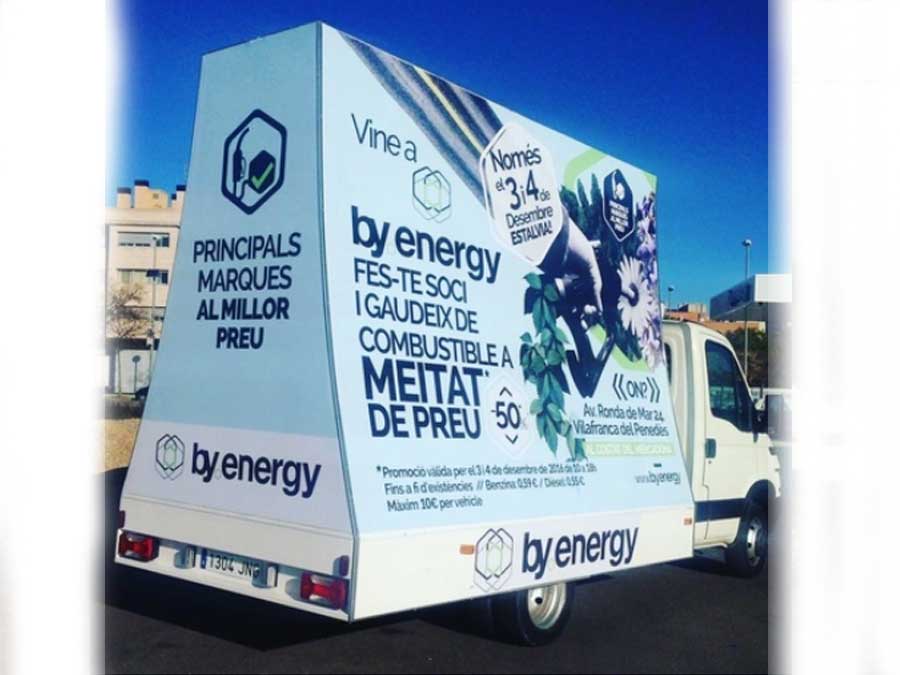 Autobús blanco estacionado con publicidad de camiones By Energy.